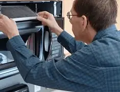 Appliance repair technician replacing a microwave vent filter in Boston, MA