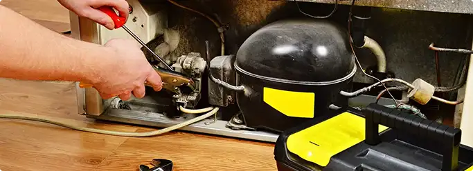 Refrigerator repair technician fixing the compressor and wiring in Boston, MA