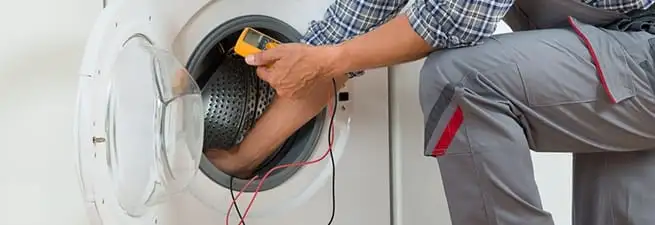 Dryer repair technician inspecting and repairing a clothes dryer in Boston, MA