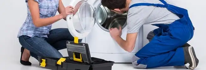 Washer repair technician inspecting a front-load washing machine with tools in Boston, MA