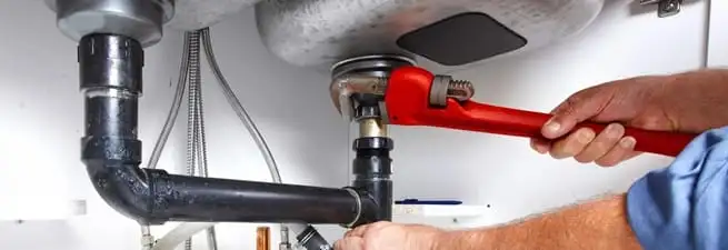 Garbage disposal repair technician tightening the sink drain and disposal connection in Boston, MA
