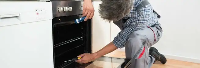 Oven repair technician inspecting and servicing an electric oven in Boston, MA