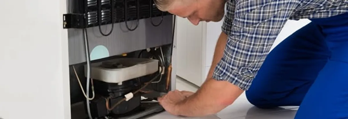 Refrigerator repair technician servicing the compressor and condenser area in Boston, MA