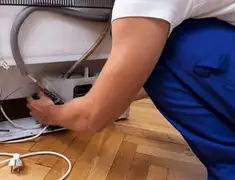 Appliance repair technician fixing refrigerator water line and connections in Boston, MA