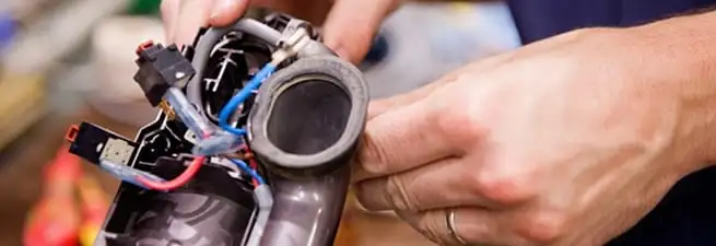 Vacuum repair technician reconnecting wiring and components in Boston, MA