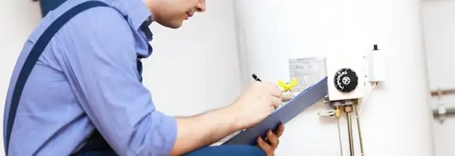 Water heater repair technician inspecting the unit and recording service notes in Boston, MA