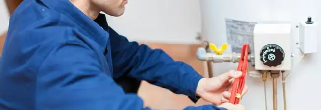Water heater repair technician adjusting the temperature control and gas valve in Boston, MA